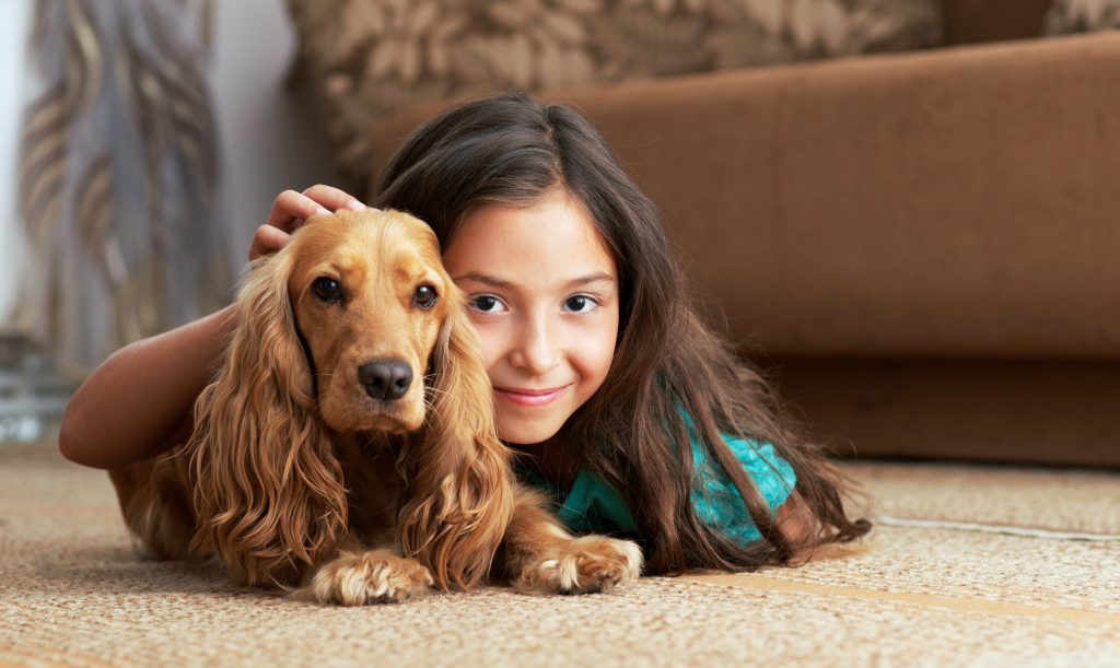 Girl and dog lying on carpet